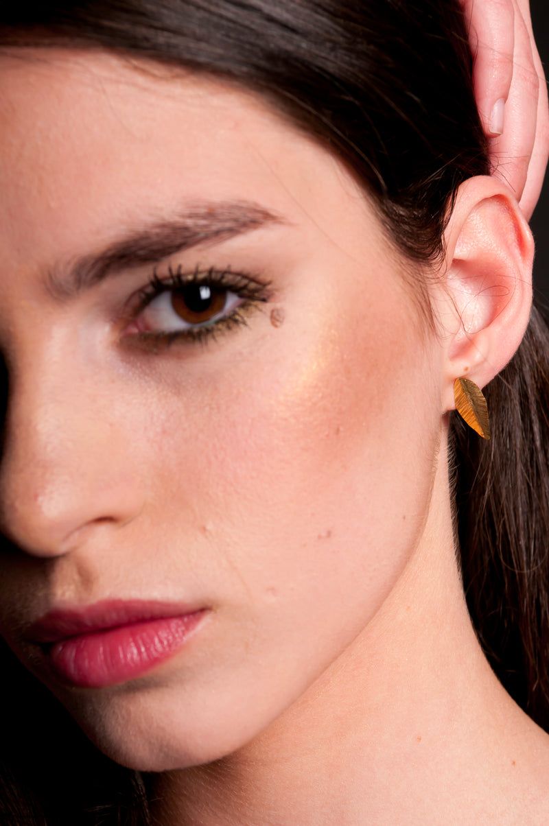 Golden leaf earrings attached to the ear