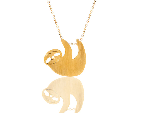 A gold sloth necklace hangs on a goldfield necklace