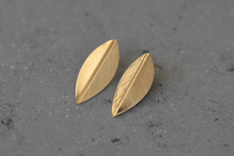 Folded gold leaf earrings close to the ear