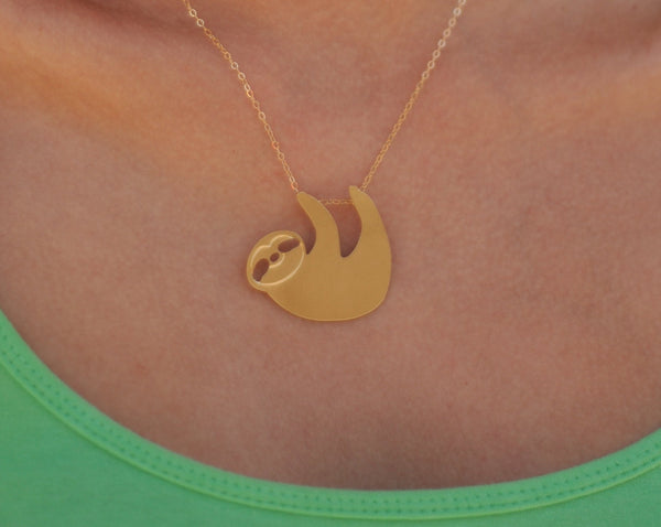 A gold sloth necklace hangs on a goldfield necklace