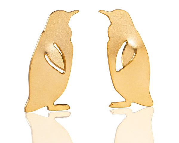 Gold penguin earrings close to the ear