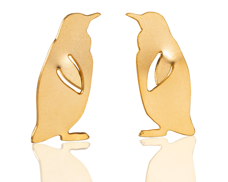 Gold penguin earrings close to the ear