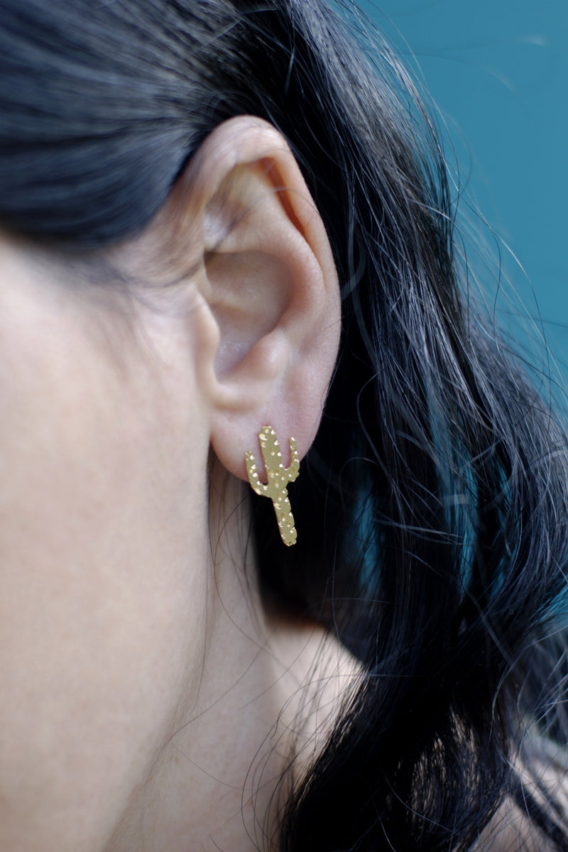 Gold cactus earrings close to the ear