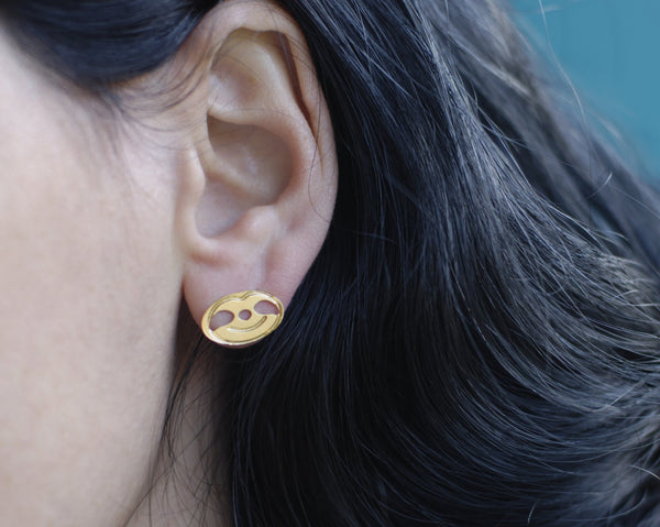 Earrings of a smiling sloth close to the ear