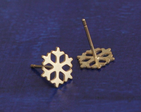 Small gold snowflake earrings close to the ear
