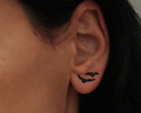 Various black flying bird earrings attached to the ear