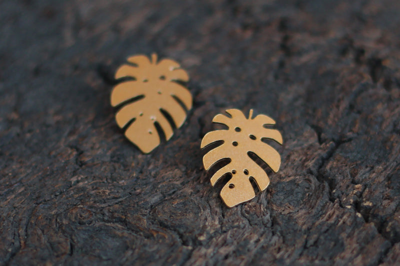 Gold Monstera leaf earrings attached to the ear