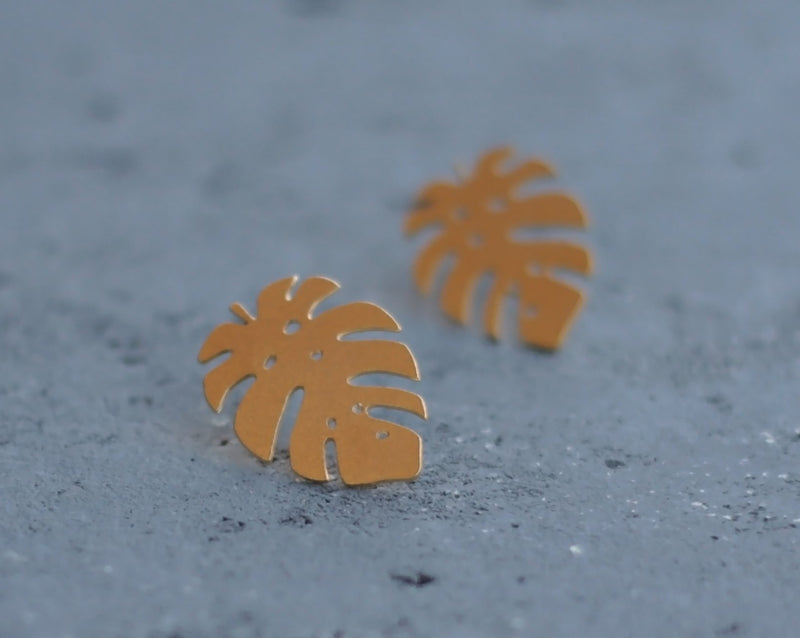 Gold Monstera leaf earrings attached to the ear