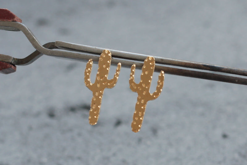 Gold cactus earrings close to the ear