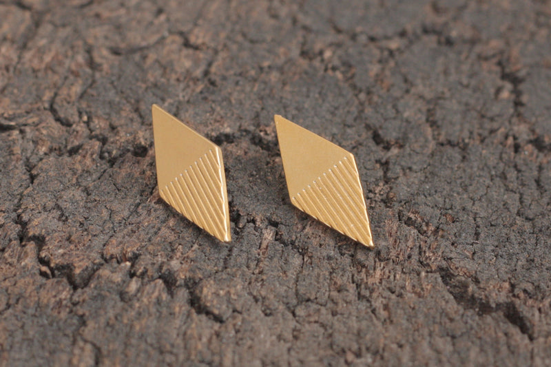 Gold rhombus earrings with stripes close to the ear