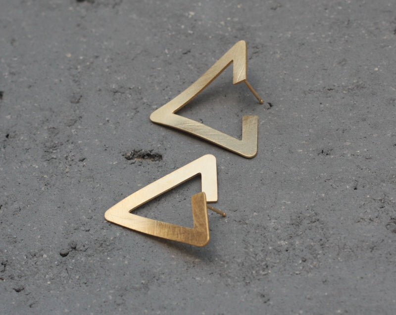 Twisted gold triangle earrings attached to the ear