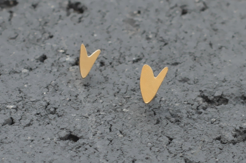 Small gold heart earrings close to the ear