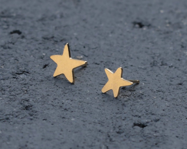 Small gold star earrings close to the ear