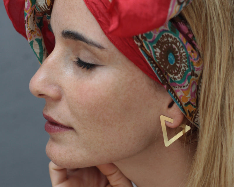 Twisted gold triangle earrings attached to the ear