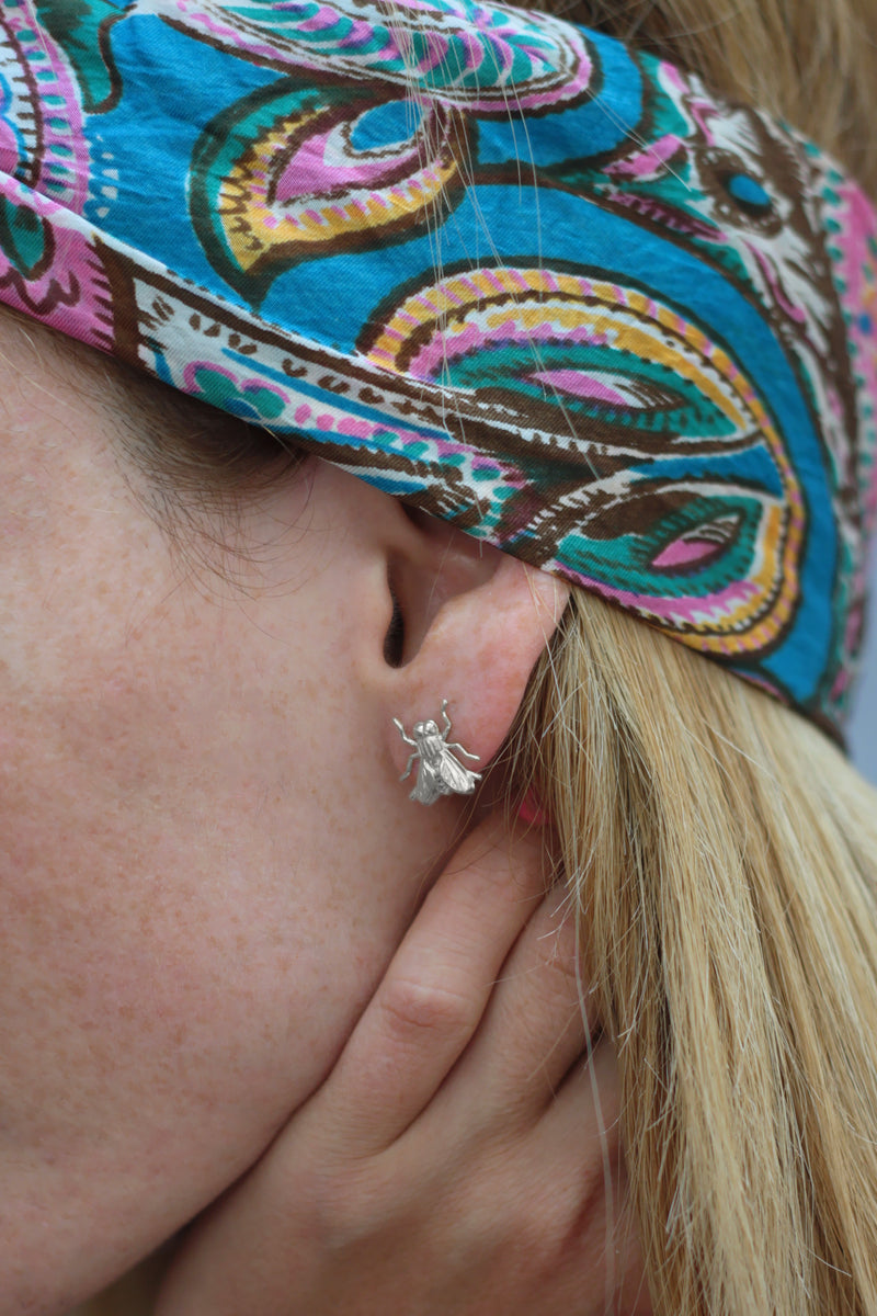 Silver fly earrings attached to the ear