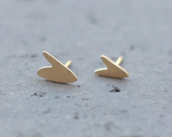 Small gold heart earrings close to the ear