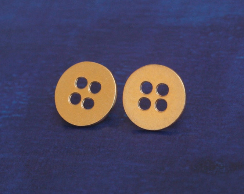 Gold button earrings close to the ear