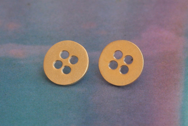 Gold button earrings close to the ear