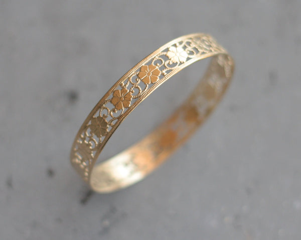 Hard golden bracelet with floral lace pattern