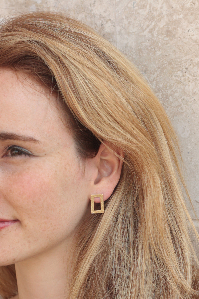 Hollow rectangle earrings set in gold close to the ear
