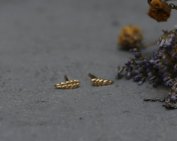 Small leaf earrings attached to a gold ear