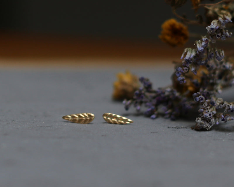 Small leaf earrings attached to a gold ear