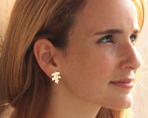 Plated gold leaf earrings close to the ear