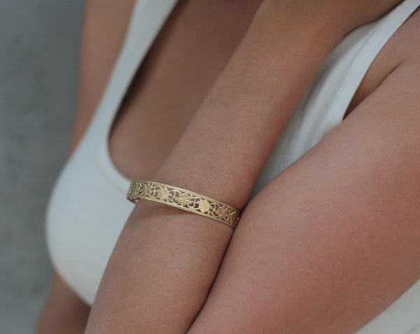 Hard golden bracelet with floral lace pattern