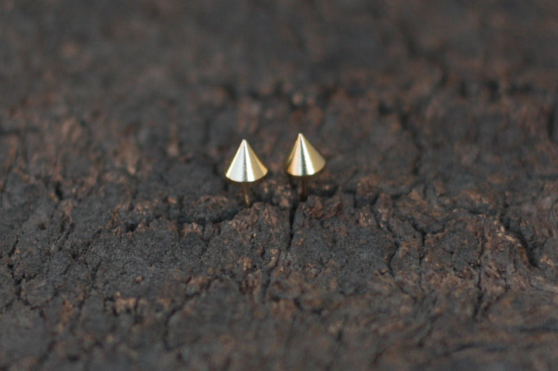 Minimalist gold spike earrings close to the ear