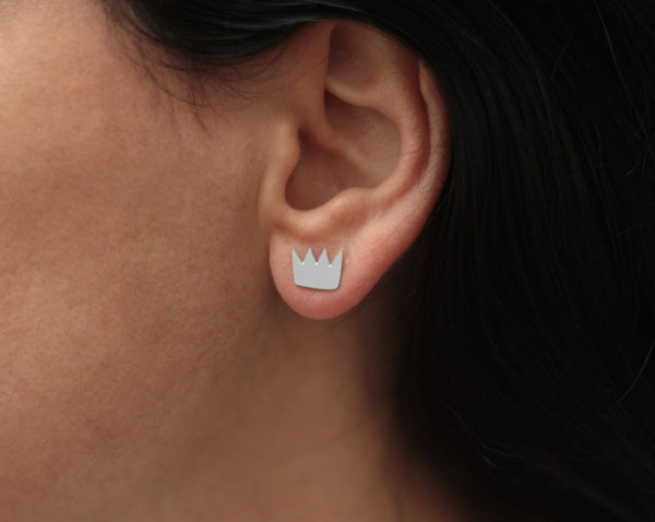 Silver crown earrings attached to the ear